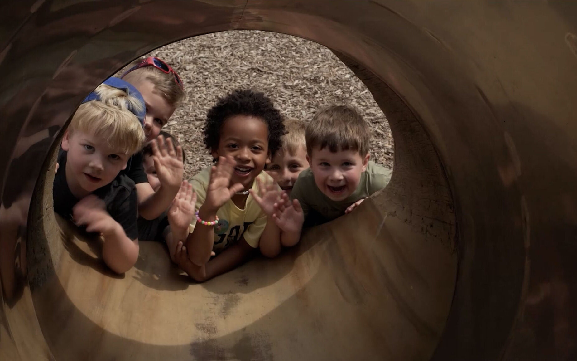 Happy children looking up into a playground slide | UPC Discovery